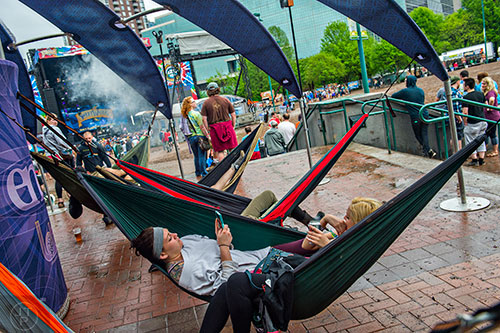 Melissa Norris (left) and Jade Grandy lay in a hammock as they listen to the Kyle Hollingsworth Band perform during the last day of the SweetWater 420 Fest at Centennial Olympic Park in Atlanta on Sunday, April 19, 2015. 