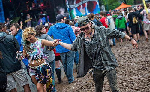 Danny Niswonger (right) tries to help Miki Meow navigate the mud during the last day of the SweetWater 420 Fest at Centennial Olympic Park in Atlanta on Sunday, April 19, 2015. 