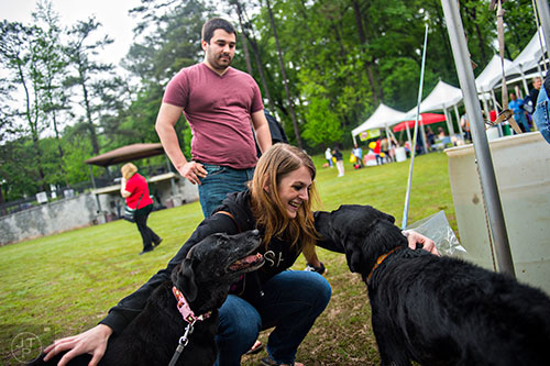 Tricia Johnston (center) pets Katie (left) and Maverick, two black labs, as John Griebel watches during the Paws for a Cause event at Glenlake Park in Decatur on Saturday, April 18, 2015.
