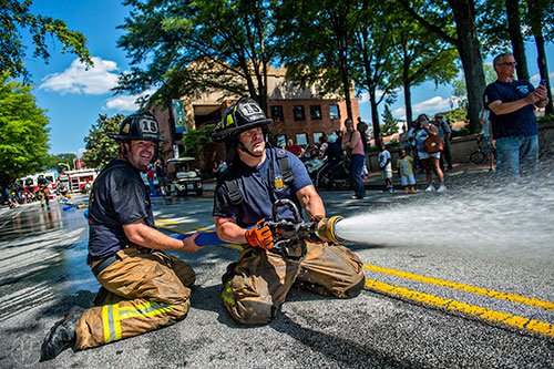 Dekalb County firefighters Patrick Hogan (left) and Brad Lanoue compete in the firefighting muster relays during the Fire in the Fourth Festival in the Old Fourth Ward neighborhood of Atlanta on Saturday, May 2, 2015.