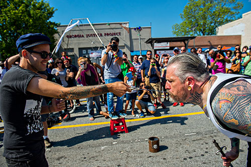 West Evans (left) pulls a sword from Captain Stab Tuggo's mouth during the Fire in the Fourth Festival in the Old Fourth Ward neighborhood of Atlanta on Saturday, May 2, 2015. 