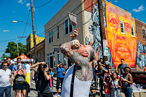 Captain Stab Tuggo swallows a handful of swords during the Fire in the Fourth Festival in the Old Fourth Ward neighborhood of Atlanta on Saturday, May 2, 2015.