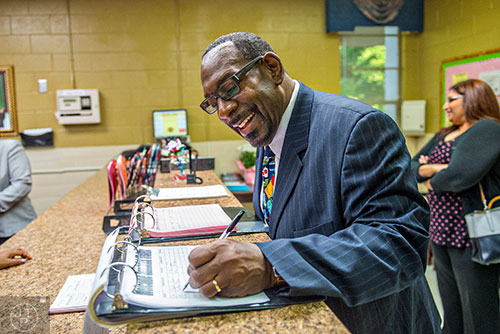 Dr. Stephen Green (center), the new superintendent for Dekalb County schools, signs into the visitors log before touring Hambrick Elementary School in Stone Mountain on Wednesday, May 20, 2015. 
