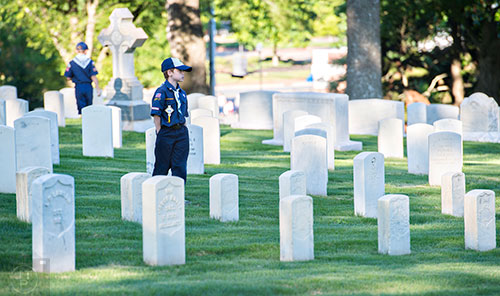 Mitchell Bishop stands amongst the tombstones before placing flags at the graves in the Marietta National Cemetery on Saturday, May 23, 2015. 