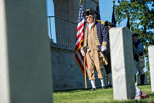George Thurmond, with the Sons of the American Revolution, carries the American flag as he leads the color guard into position at the Marietta National Cemetery on Saturday, May 23, 2015. 