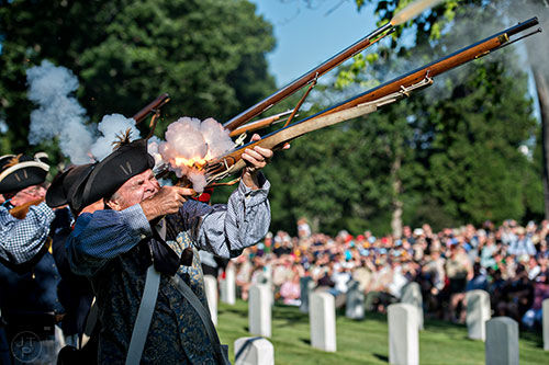 Bruce Maney (left), with the Sons of the American Revolution, fires his musket during a salute at the Marietta National Cemetery on Saturday, May 23, 2015. 