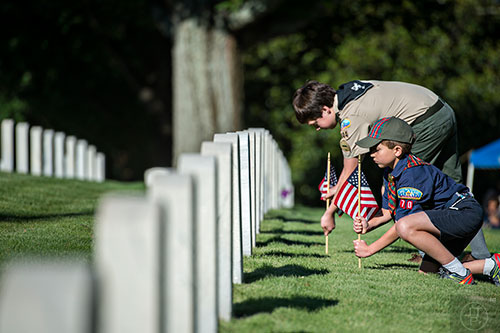 Bennett Robertson (right) and Paul Thornburgh plant flags at two of the graves in the Marietta National Cemetery on Saturday, May 23, 2015. 