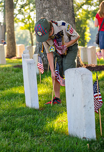 Will Hearn plants a flag at one of the graves in the Marietta National Cemetery on Saturday, May 23, 2015. 