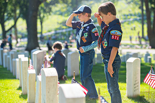 Liam Gurley (right) and Hayden Krueger salute after placing flags at two of the graves in the Marietta National Cemetery on Saturday, May 23, 2015. 