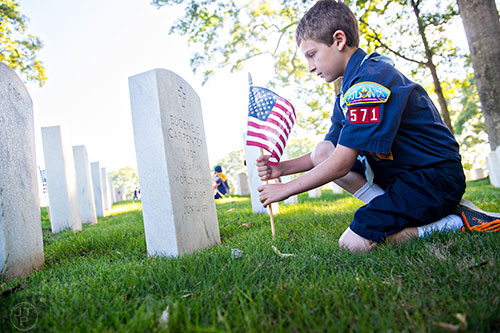David Doyle plants a flag at one of the graves in the Marietta National Cemetery on Saturday, May 23, 2015. 