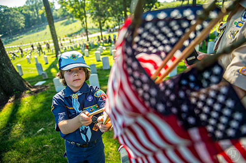 Austin Hampson (left) grabs his next flag to place at one of the graves in the Marietta National Cemetery on Saturday, May 23, 2015. 