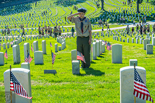 Adam Palmer salutes after placing a flag at one of the graves in the Marietta National Cemetery on Saturday, May 23, 2015. 