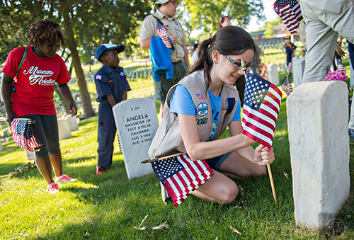 Caroline Solomon (right) plants a flag at one of the graves in the Marietta National Cemetery on Saturday, May 23, 2015. 