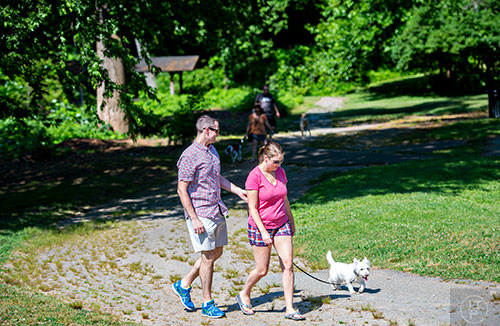 Andrew Downard (left) and Christine Anderson walk down the trail with Sparky, a westie, during Bark at the Park at Brookhaven Park on Saturday, May 23, 2015.  