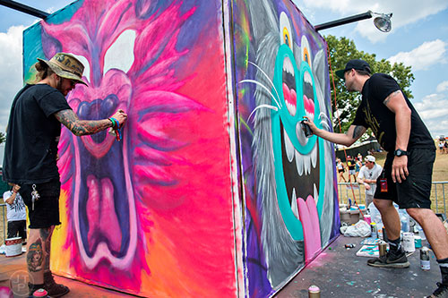 Wolfdog (left) and Greg Mike use cans of spray paint to create a piece of artwork during the CounterPoint Festival at Kingston Downs in Rome on Sunday, May 24, 2015. 
