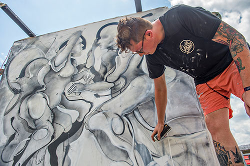 Trey Moseley uses spray paint to create a piece of artwork during the CounterPoint Festival at Kingston Downs in Rome on Sunday, May 24, 2015. 