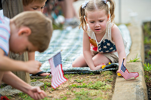 Alexis Lucas (right) and Jesse Austin hold American flags as they wait for the start of the annual Dacula Memorial Day Parade on Monday, May 25, 2015. 
