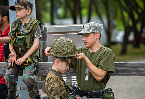 Timothy Beauchamp (right) helps his brother Samuel with his helmet as they and their other brother Jonathan wait for the start of the annual Dacula Memorial Day Parade on Monday, May 25, 2015. 