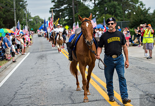 Carey Davis (right) leads a symbolic riderless horse down Dacula Rd. during the annual Dacula Memorial Day Parade on Monday, May 25, 2015. 