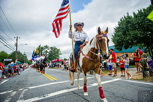 Ann Harris carries an American flag down Dacula Rd. while on horseback during the annual Dacula Memorial Day Parade on Monday, May 25, 2015. 