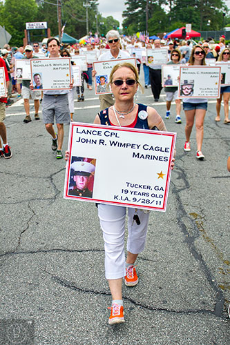 Carolyn Cagle (center) carries a photo of her son John Wimpey Cagle, who was killed in action in 2011, as she marches with the Fallen Heroes of Georgia during the annual Dacula Memorial Day Parade on Monday, May 25, 2015. 
