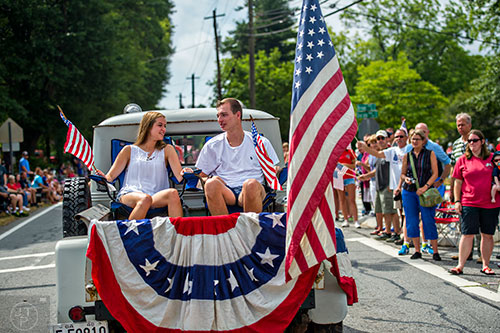 Jillian Elmer (left) and Ethan Reynolds sit in the bed of a pick up truck as they ride down Dacula Rd. during the annual Dacula Memorial Day Parade on Monday, May 25, 2015. 