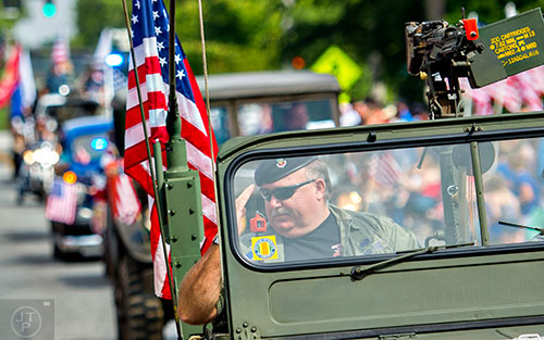 Elton Hassell (center) salutes to the crowd as he rides in a military jeep during the annual Dacula Memorial Day Parade on Monday, May 25, 2015. 