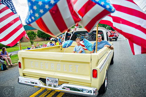 Steven Phillips (left) and his father Scott ride in the back of a Chevrolet pick up truck during the annual Dacula Memorial Day Parade on Monday, May 25, 2015. 