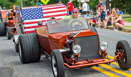 Jim Thompson (right) waves to the crowd as he drives the parade route during the annual Dacula Memorial Day Parade on Monday, May 25, 2015. 