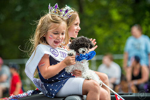 Ariel Jones (left) waves her dog Roxie's paw at the crowd during the annual Dacula Memorial Day Parade on Monday, May 25, 2015. 