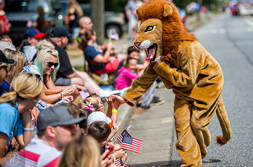 Dressed as a lion, Lexi Kent hands out high fives to the crowd during the annual Dacula Memorial Day Parade on Monday, May 25, 2015. 