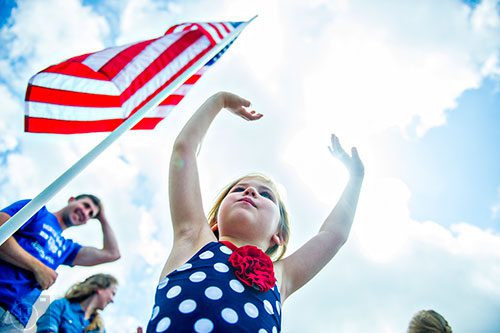 Aubrey Lecture (center) waves as the annual Dacula Memorial Day Parade passes by on Monday, May 25, 2015. 