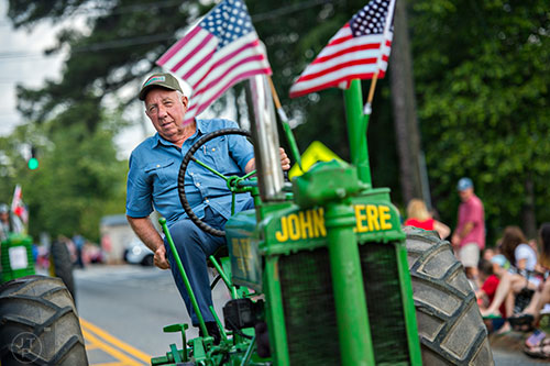 Harold Flannigan drives his John Deere tractor down the parade route during the annual Dacula Memorial Day Parade on Monday, May 25, 2015. 