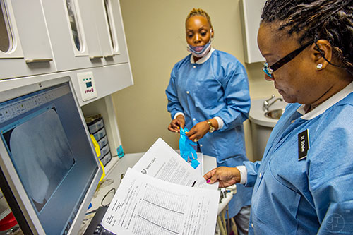 Dr. Katrina Schuler-Bacon (right) takes a look at Marcet Love's dental history at Mercy Care's dental clinic off of Decatur St. in Atlanta on Tuesday, May 19, 2015. Schuler-Bacon and her assistant DaJanea Rogers (left) had to pull one of Love's teeth during his visit to the clinic. 