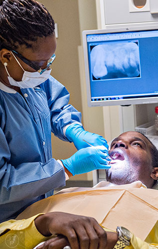 Dr. Katrina Schuler-Bacon (left) examines Marcet Love's teeth during a visit to Mercy Care's dental clinic at their facility off of Decatur St. in Atlanta on Tuesday, May 19, 2015. Love had a tooth pulled during his visit to the clinic.