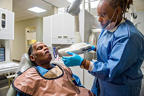 DaJanea Rogers (right) sets up an x-ray machine to take a look at Andre Bencent's teeth during a visit to Mercy Care's dental clinic at their facility off of Decatur St. in Atlanta on Tuesday, May 19, 2015. Bencent's remaining teeth will have to be pulled and he will hopefully be fitted for dentures. 