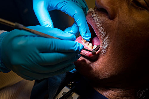 Andre Bencent (right) has his teeth examined by Dr. Katrina Schuler-Bacon during a visit to Mercy Care's dental clinic at their facility off of Decatur St. in Atlanta on Tuesday, May 19, 2015. Bencent's remaining teeth will have to be pulled and he will hopefully be fitted for dentures. 