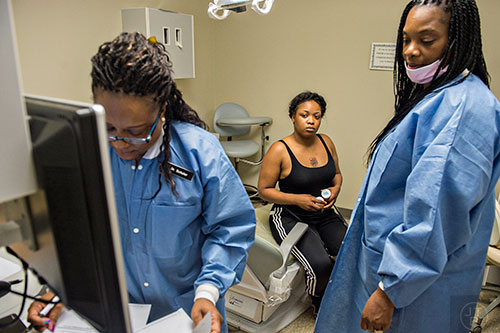 Deenay Vestal (center) waits for final instructions from Dr. Katrina Schuler-Bacon (left) and Vickie Francis during a visit to Mercy Care's dental clinic at their facility off of Decatur St. in Atlanta on Tuesday, May 19, 2015. Vestal received two prescriptions for a wisdom tooth that is cutting through her gums.