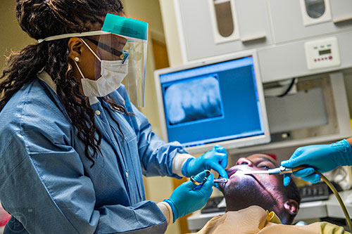 Dr. Katrina Schuler-Bacon (left) gives Marcet Love a shot of numbing medication before pulling one of his teeth during a visit to Mercy Care's dental clinic at their facility off of Decatur St. in Atlanta on Tuesday, May 19, 2015. 