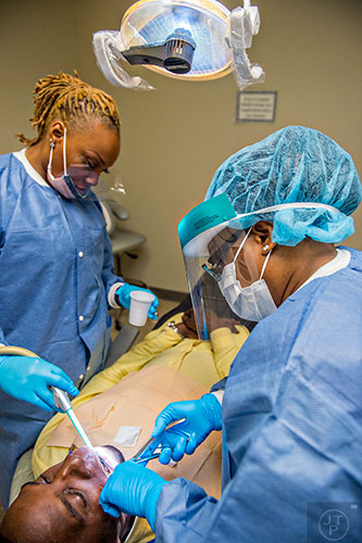 Dr. Katrina Schuler-Bacon (right) and DaJanea Rogers pull one of Marcet Love's teeth during a visit to Mercy Care's dental clinic at their facility off of Decatur St. in Atlanta on Tuesday, May 19, 2015. 