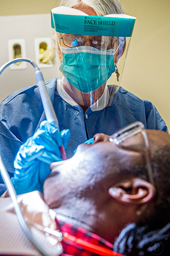 Cindy Pickard (top) cleans Cedric Russell's teeth during a visit to Mercy Care's dental clinic at their facility off of Decatur St. in Atlanta on Tuesday, May 19, 2015. 