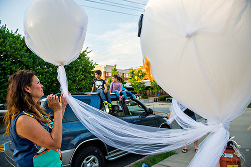 Daphne Cobb (left) ties helium balloons into her family's lantern before the start of the Decatur Lantern Parade at Color Wheel Studio on Friday, May 15, 2015.