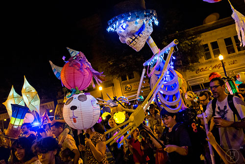Coleman Marker (right) carries a skeleton lantern on his back as he marches in the Decatur Lantern Parade on Friday, May 15, 2015.