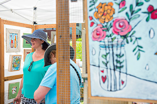 Susan Darcy Fuller (left) and her mother Nancy Darcy look at the artwork in Jenni Horne's booth during the Kirkwood Spring Fling at Bessie Branham Park on Saturday, May 16, 2015.