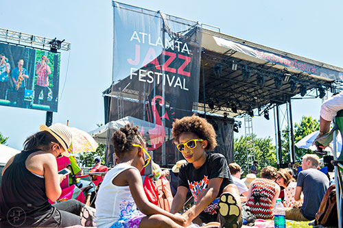 Demi Craft (right) plays with Lyric Amador as they sit in front of the main stage during the Atlanta Jazz Fest at Piedmont Park on Saturday, May 23, 2015.