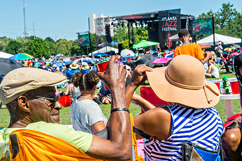 Julian Knox (left) and his wife Maggie sit in the sun as they listen to The Rad Trads perform during the Atlanta Jazz Fest at Piedmont Park on Saturday, May 23, 2015.