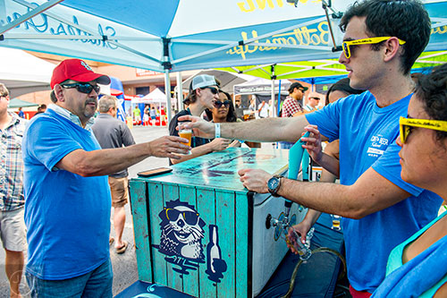 Denny Boomhower (left) is handed a beer by Efrain Cermeno during the Georgia Craft Beer Festival outside of Red Brick Brewing in Atlanta on Saturday, May 30, 2015. 