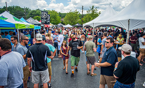 Hannah Williams (center) holds hands with Anthony Buda as they walk past brewers' tents during the Georgia Craft Beer Festival outside of Red Brick Brewing in Atlanta on Saturday, May 30, 2015. 
