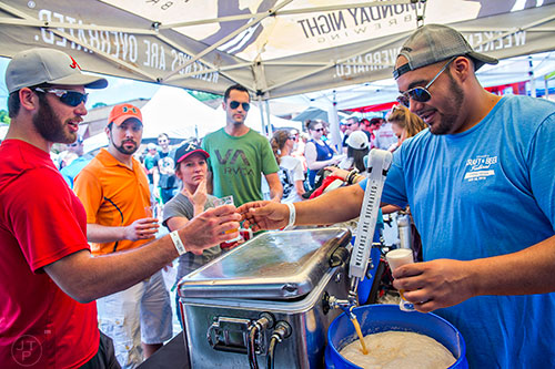 Antonio Gonzalez (right) hands Jacob Bagley a sampling of beer during the Georgia Craft Beer Festival outside of Red Brick Brewing in Atlanta on Saturday, May 30, 2015. 