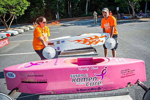 Natalie Christianson (left) and Jim Russell load cars onto a trailer as racers prepare for the All American Dunwoody Soap Box Derby at the First Baptist Church of Atlanta in Dunwoody on Saturday, June 6, 2015. 
